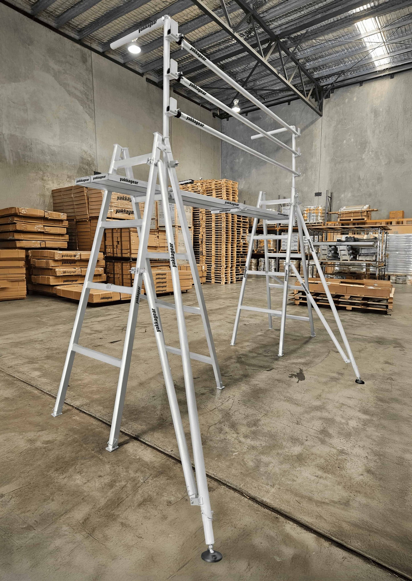 Yakka Gear Australia Handrail Trestle System single bay—aluminium trestle scaffold with guard rails and plank platform, set up in a warehouse for safe elevated access, painting and maintenance work across Australia.