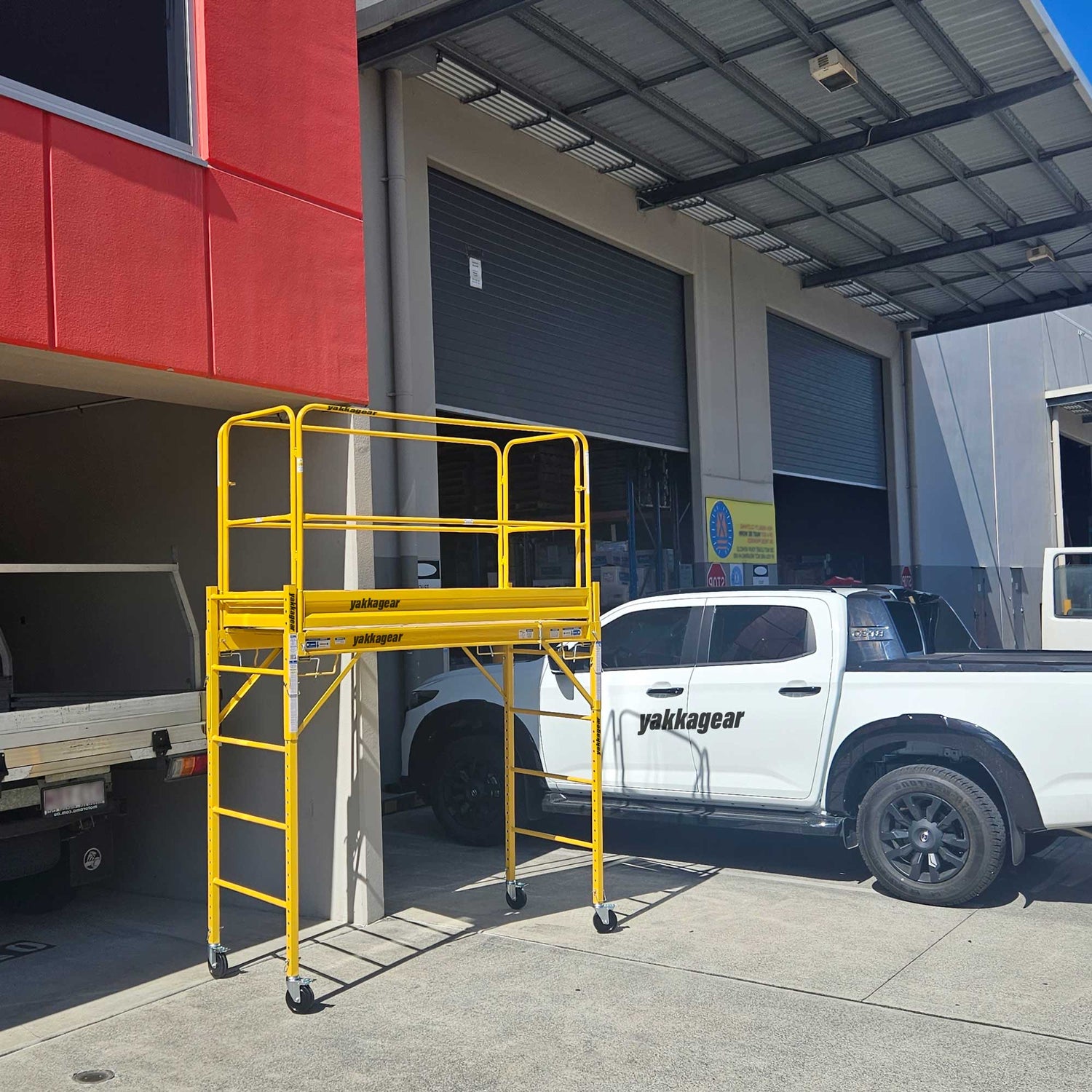 Complete Rapid Mobile Scaffold system by Yakka Gear Australia in warehouse, 3.8m reach with guard rails at full height, 1.87m L x 0.73m W platform, 1.81m adjustable platform height, sturdy steel frame with outriggers and lockable castor wheels.