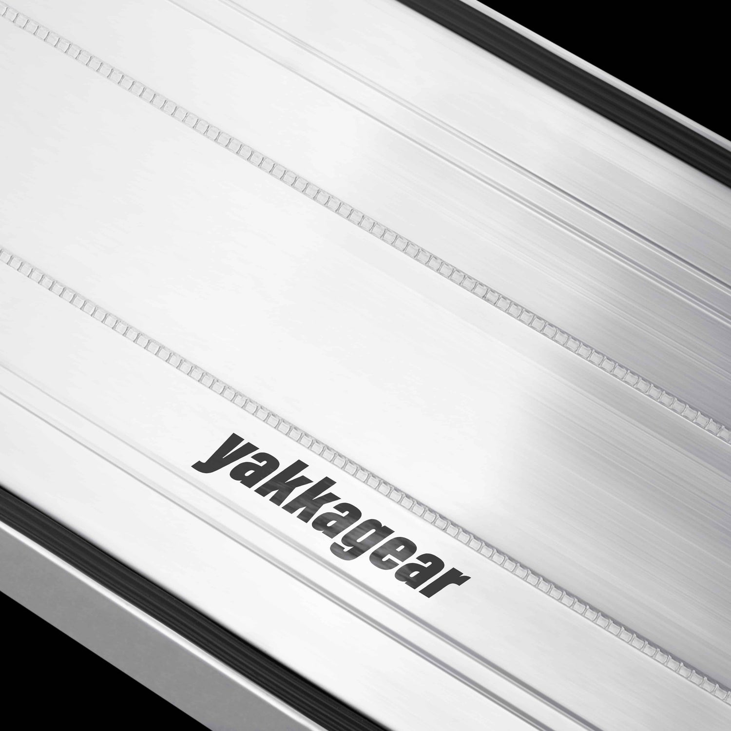 Close-up of an aluminium plank against a black background, highlighting the detailed non-slip aluminium treads and the removable rubber inserts. The image focuses on the traction-enhancing surface design, offering a clear view of the safety features used by tradies for secure footing on worksites.