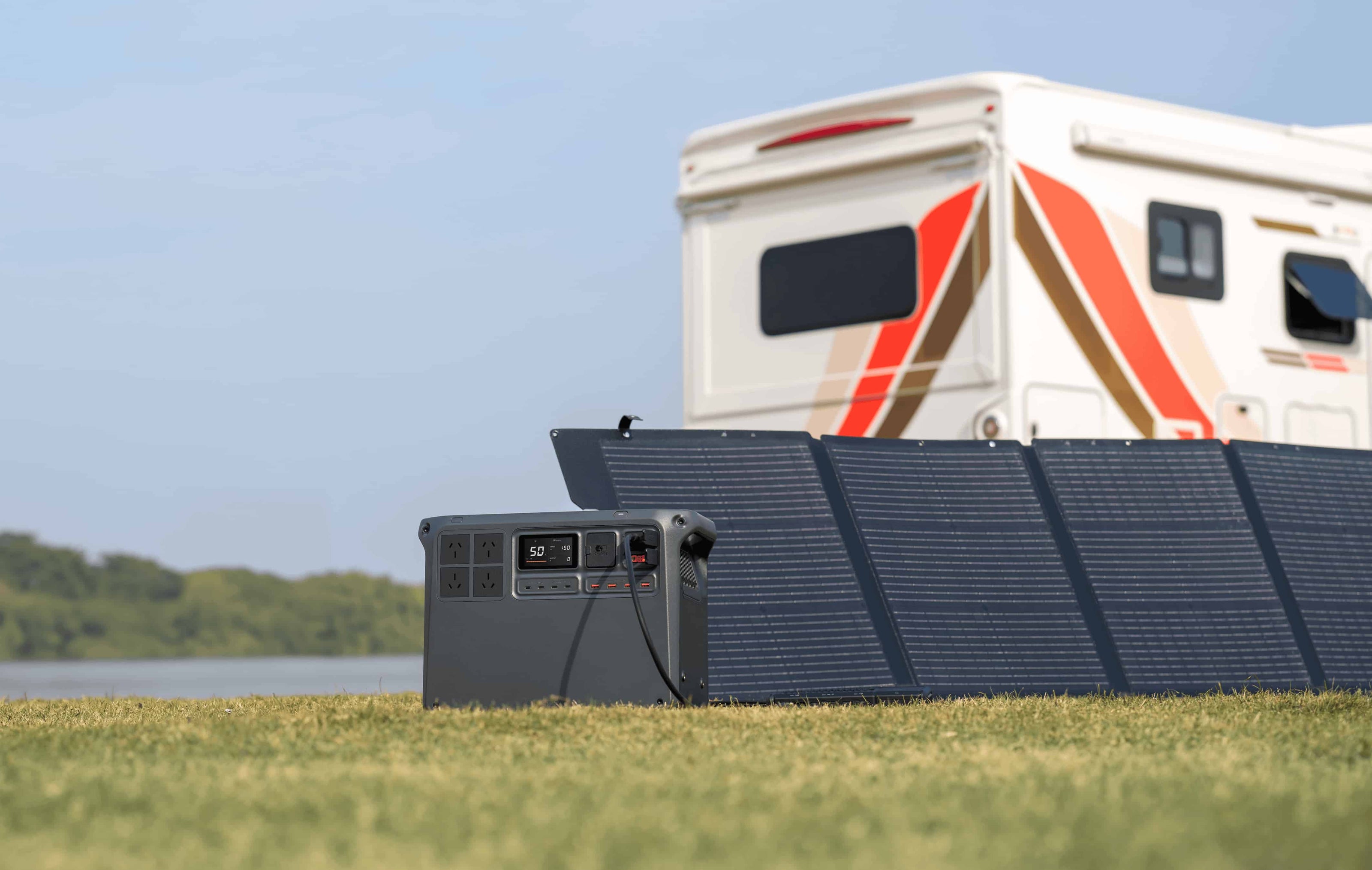DJI Power 2000 charging via solar panel in front of a caravan on grass — reliable off-grid power setup for tradies, 4WD touring, and remote job sites; ideal for camping and mobile worksites, available from Yakka Gear.