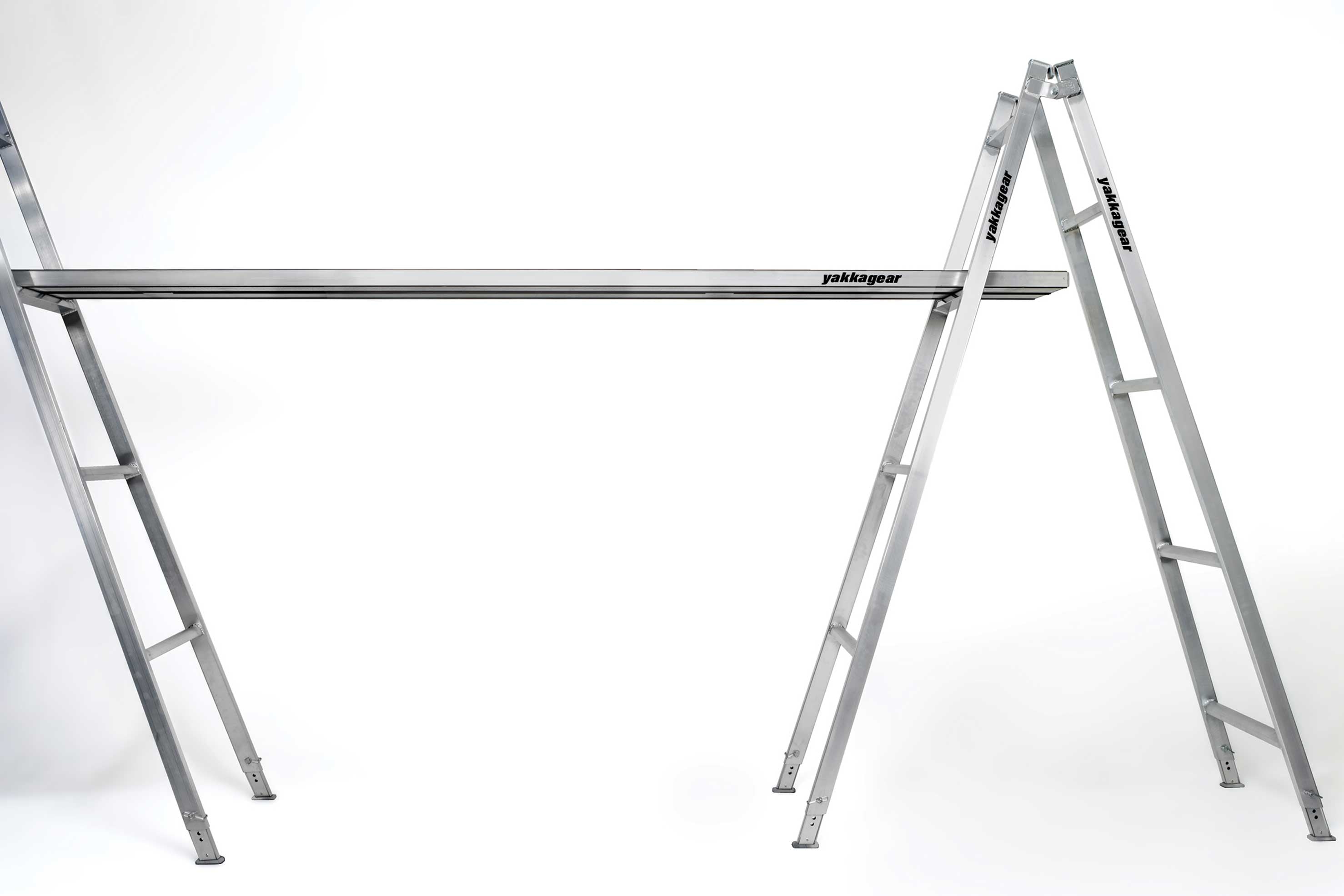 Yakka Gear Australia Aluminium Planks as access equipment. Various sized planks available including 2.5m, 3m, 3.6m, 4m, 5m and 6m planks. Shown being used across two trestle ladders. Can also be used as access equipment on scaffolding or trestles, as hungry boards, ramps, saw horse, plastering stool, steps for stairs, side steps to a 4WD vehicle or boat trailer. View from above with white background. 