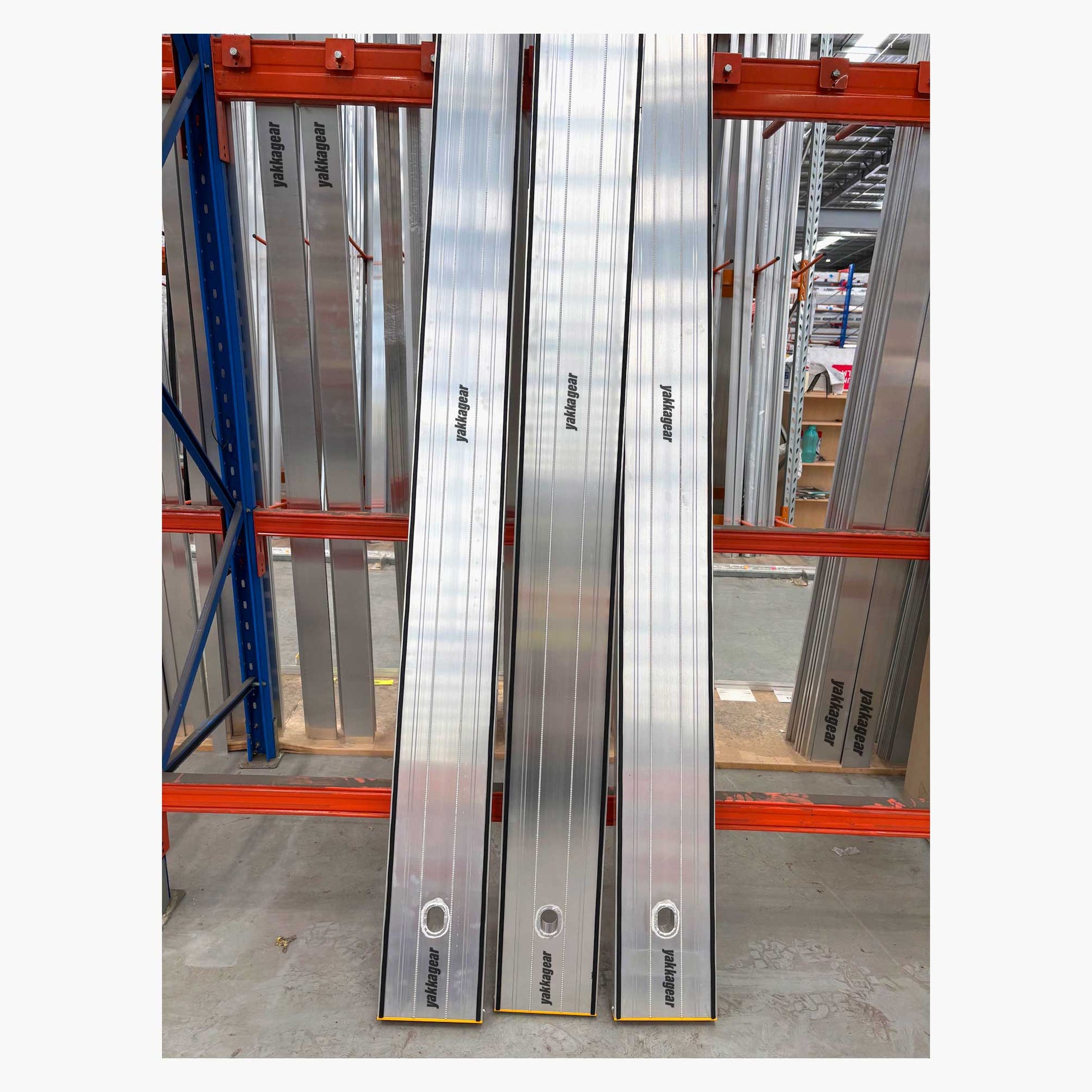 Three lockable planks leaning securely against a storage rack inside a warehouse, Yakka Gear equipment, Australia.